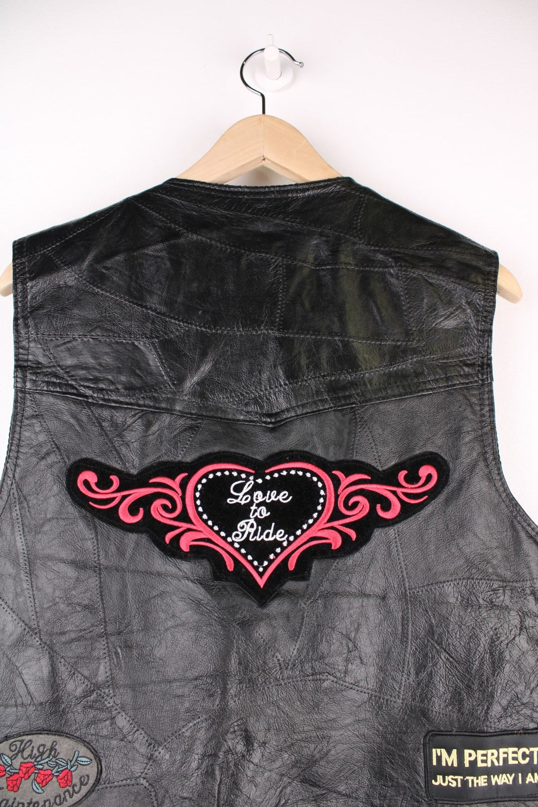 Leather Biker Vest in a black colourway, button up with a v neck collar, and has multiple patches embroidered around the gilet.