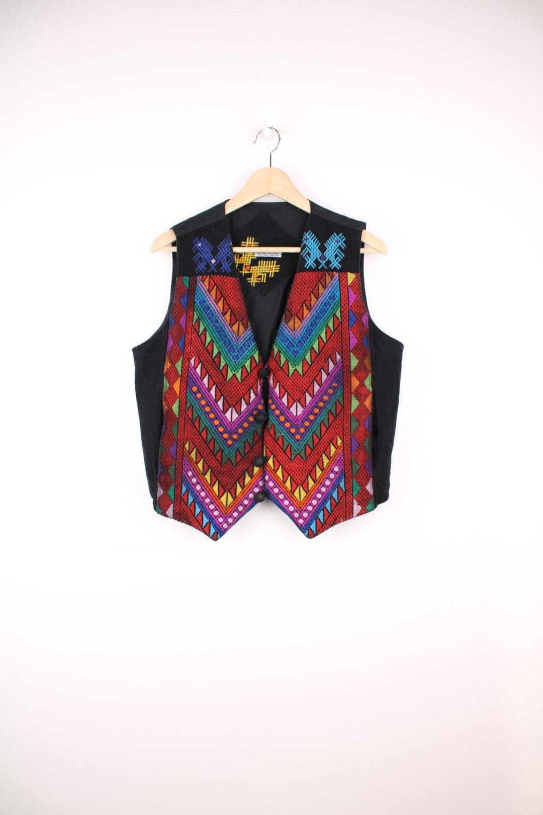 Vintage black vest with multicoloured embroidery, button closure, and a buckled waist adjuster on the back. Handmade in Guatemala.