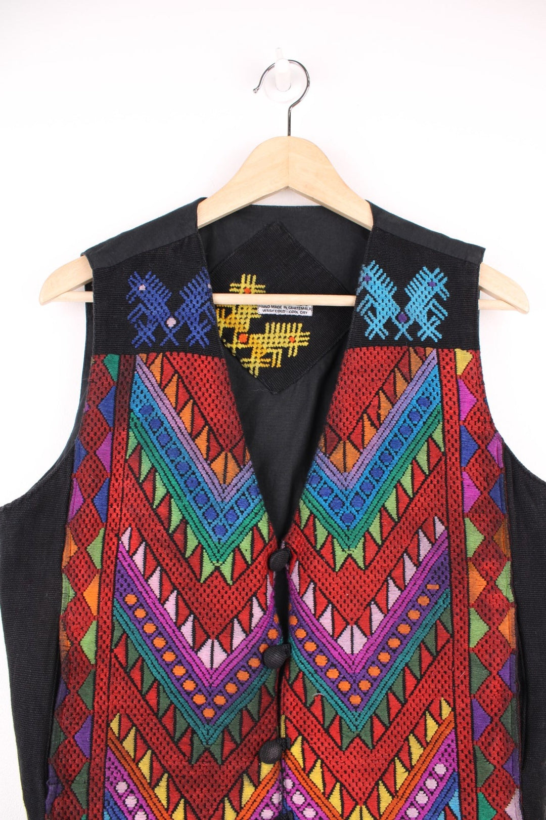 Vintage black vest with multicoloured embroidery, button closure, and a buckled waist adjuster on the back. Handmade in Guatemala.