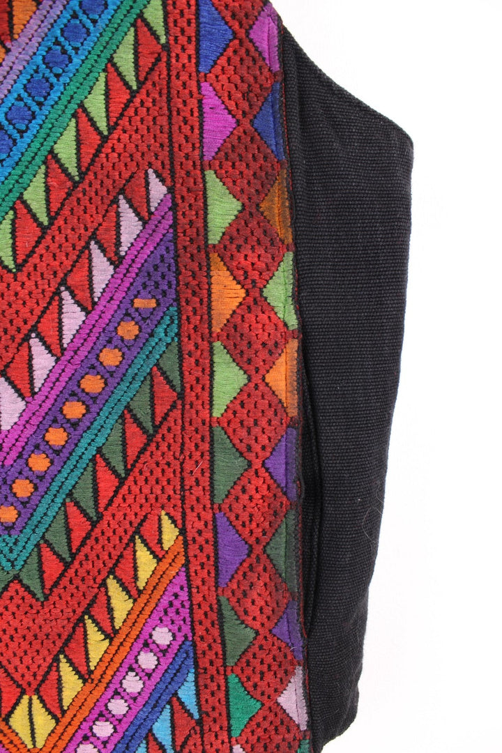 Vintage black vest with multicoloured embroidery, button closure, and a buckled waist adjuster on the back. Handmade in Guatemala.