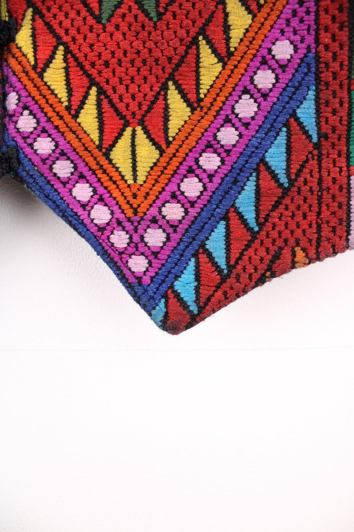 Vintage black vest with multicoloured embroidery, button closure, and a buckled waist adjuster on the back. Handmade in Guatemala.