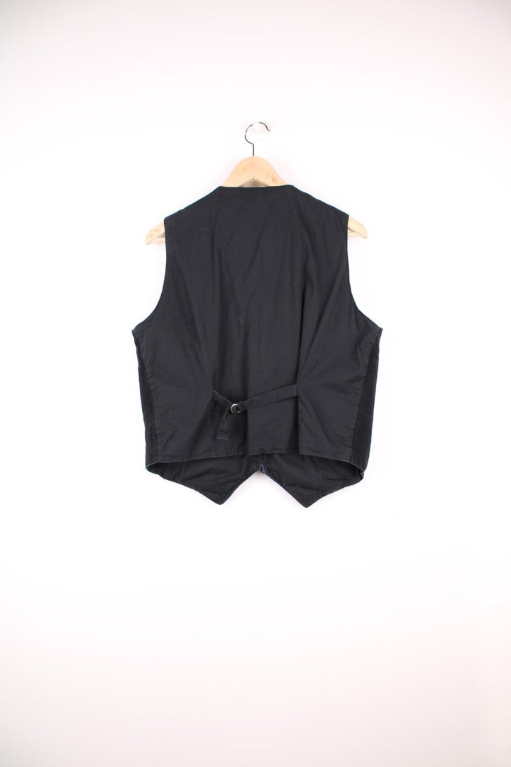 Vintage black vest with multicoloured embroidery, button closure, and a buckled waist adjuster on the back. Handmade in Guatemala.