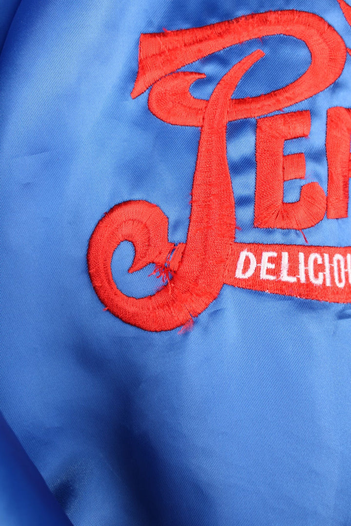 Blue 'Pepsi-Cola' personalised bomber jacket with white striped accents around the collar and cuffs. Snap closure, with the Pepsi-Cola logo embroidered on the chest and back.