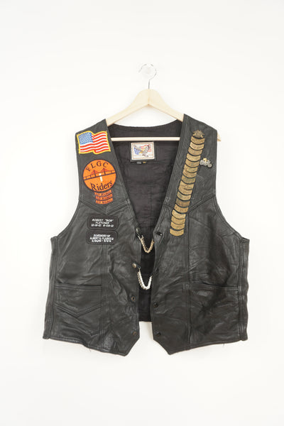 Men's vintage Harley Davidson Owners Group black leather vest with lots of commemorative patches, pins and bike chain details