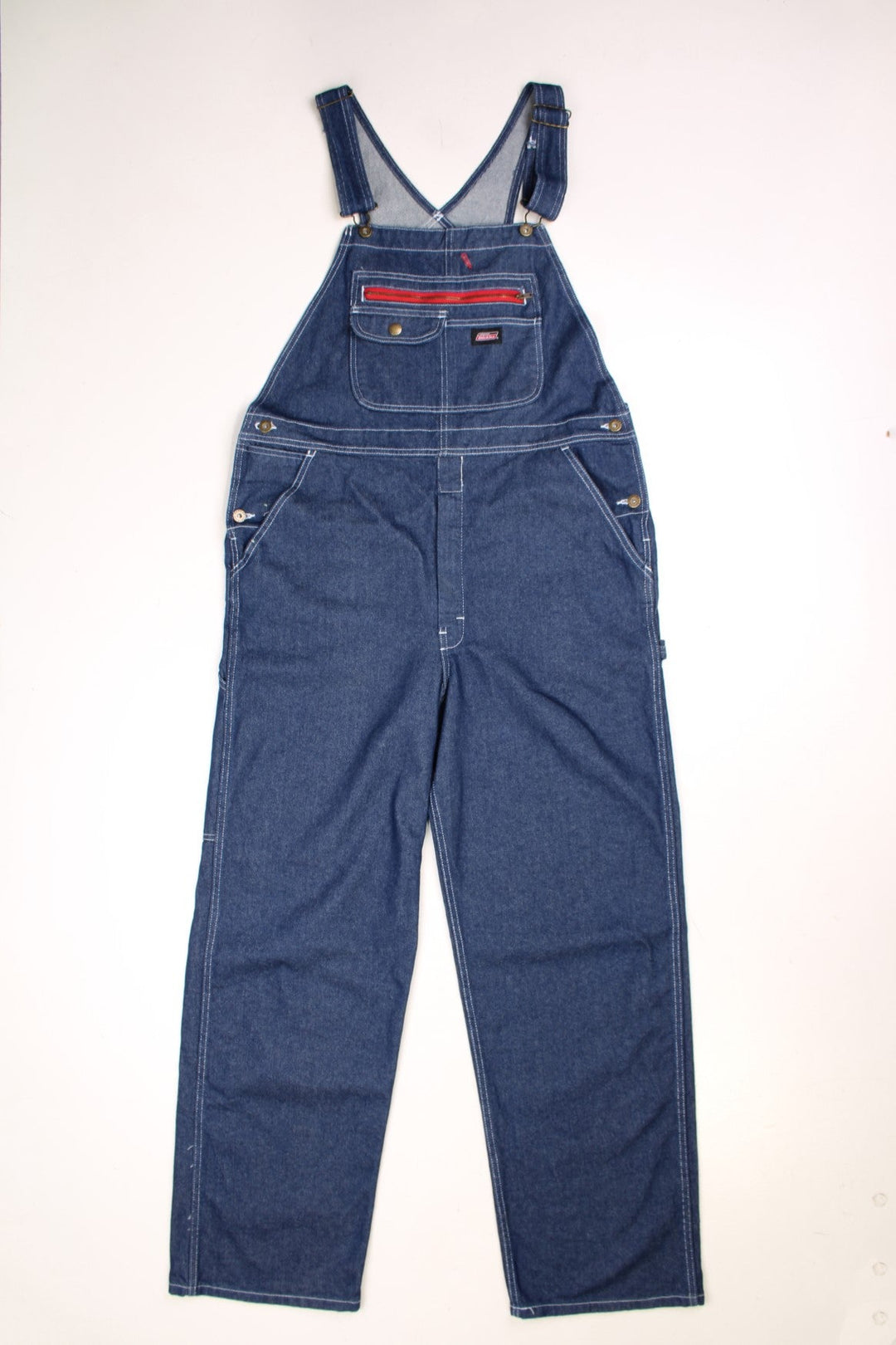 Dark wash Dickies dungarees with multiple pockets, white contrast stitch, a red accented zip pocket, and Dickies logos on the front and back.