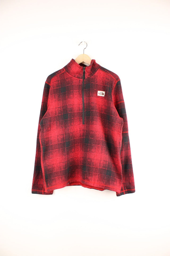 The North Face red and black check fleece with 1/2 zip closure and a white logo patch.