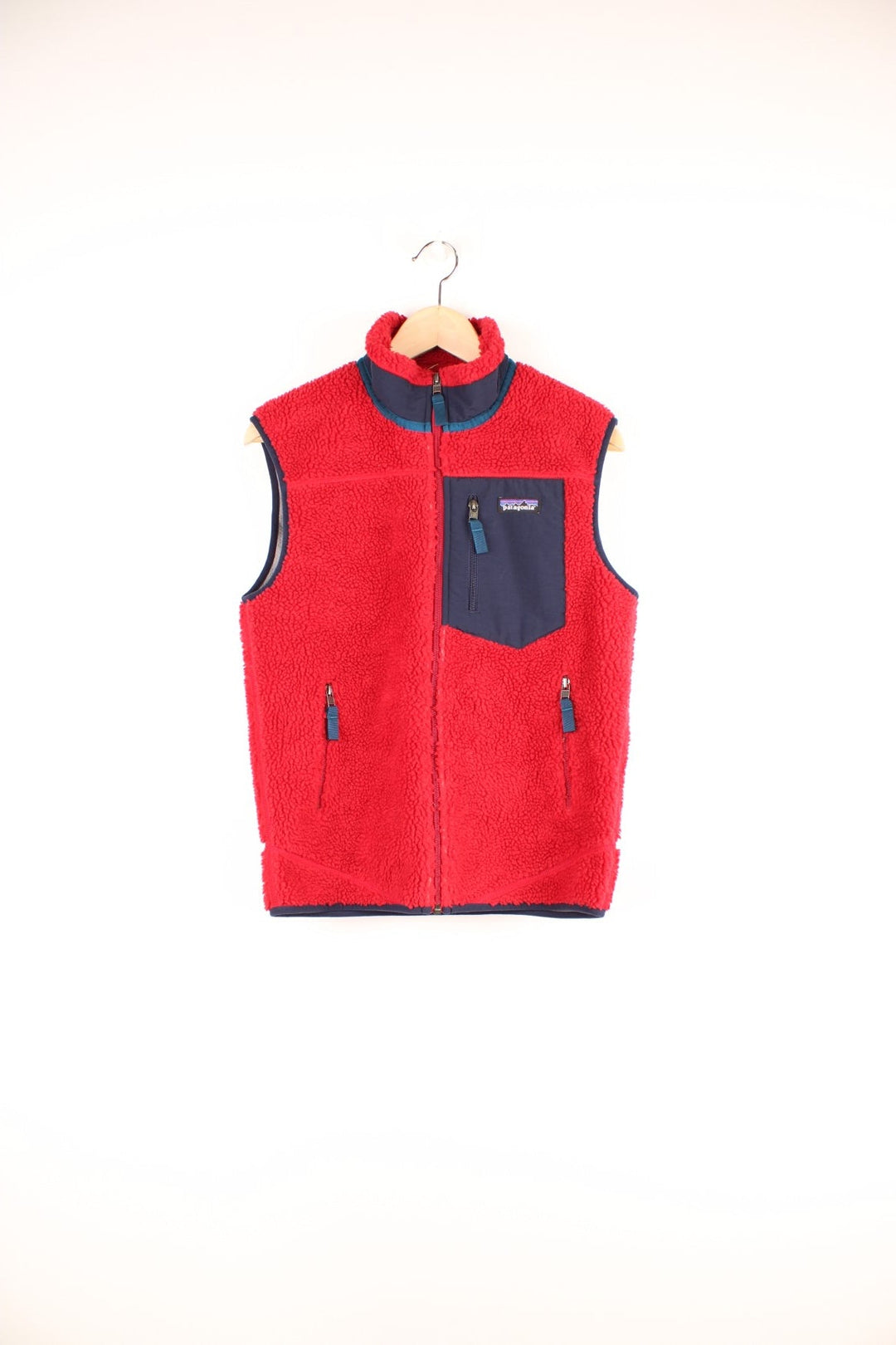 Red Patagonia fleece gilet with blue accents, zip closure, three zipped logos and an embroidered logo patch.