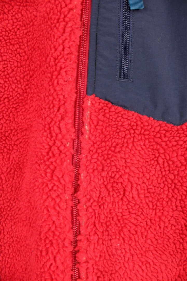 Red Patagonia fleece gilet with blue accents, zip closure, three zipped logos and an embroidered logo patch.