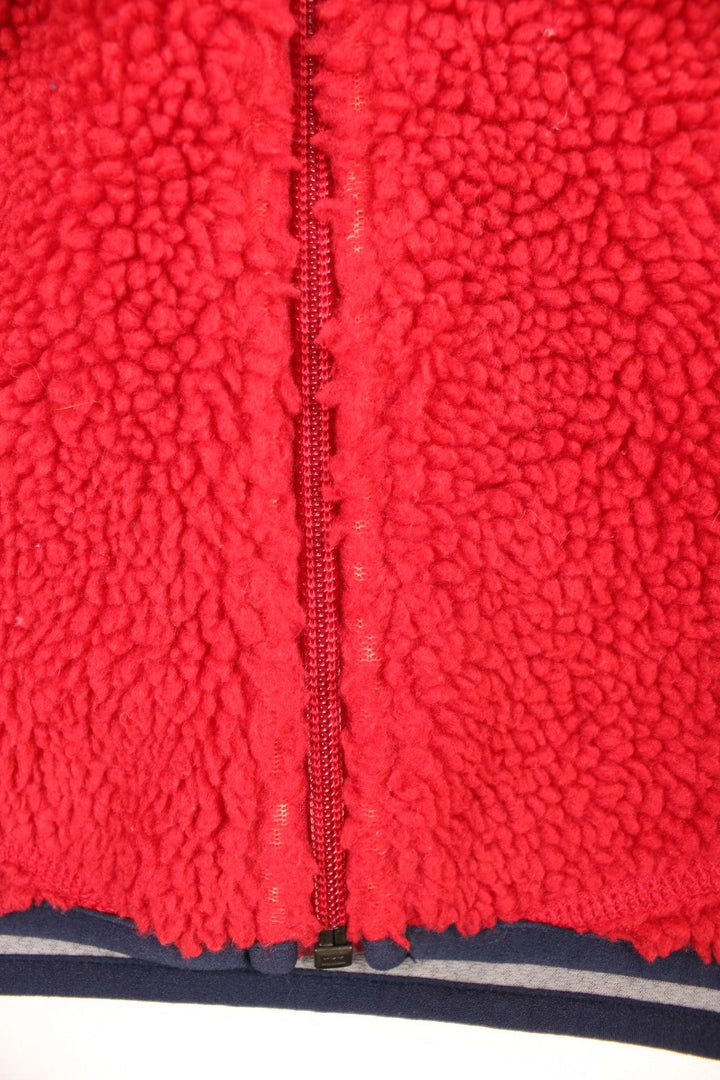 Red Patagonia fleece gilet with blue accents, zip closure, three zipped logos and an embroidered logo patch.