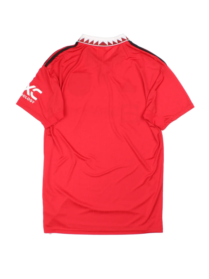 Manchester United 2002/23 Adidas Football Shirt in the red home kit colourway, features printed logos and badge on the front with the classic adidas 3 stripe on the sleeve and button collar.