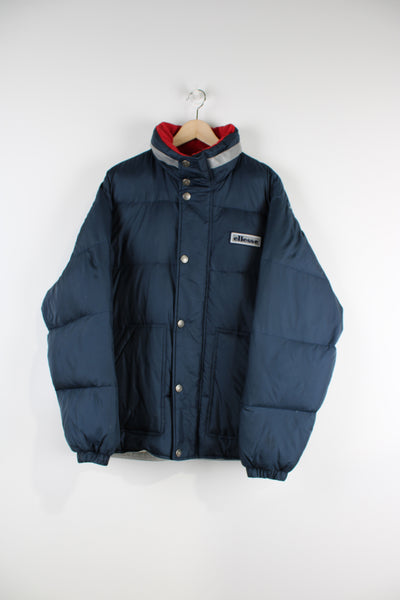 Ellesse Navy puffer Coat with embroidered logo on chest and fold away hood.  good condition - some small scuffs to the fabric inside the hood  Size in Label:  Mens S - Measures lore like a M