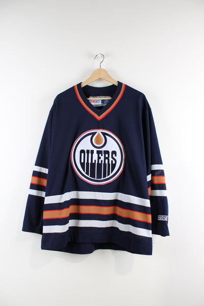 Vintage CCM Edmonton Oilers NHL jersey with embroidered lettering and badges.  good condition  Size in Label:   Mens L - Measures more like an XL  Our Measurements:  Chest: 28 inches Length: 30 inches
