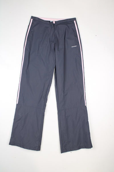 Vintage Reebok tracksuit bottoms in grey with pink and white stripes going down the sides, and embroidered logo on the front.