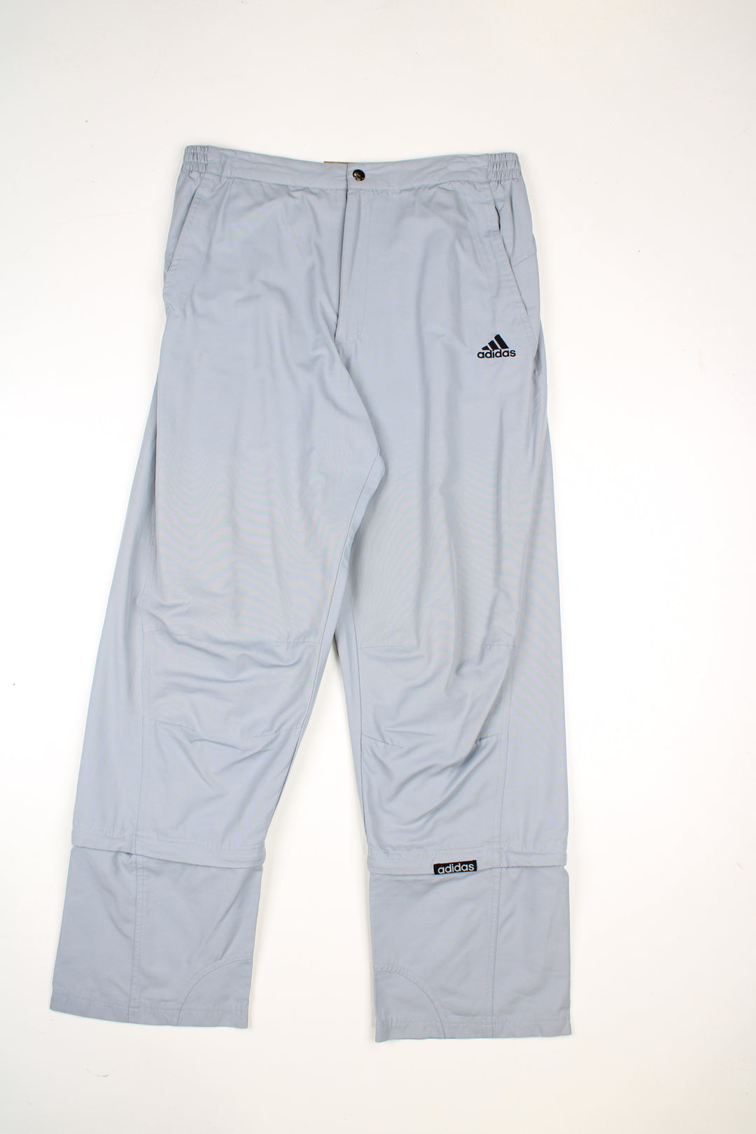 Vintage Adidas tracksuit bottoms in a grey colourway, elasticated waist, multiple pockets,  has logo embroidered on the front and detachable zip on the legs to make them quarter length.