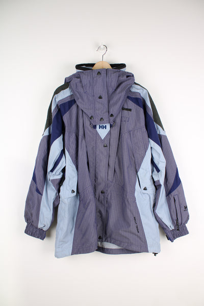 Vintage Helly Hansen Tech jacket in a blue colourway, zip up, detachable hood, multiple pockets, and has logo embroidered on the front.