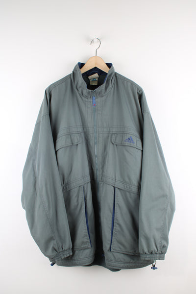 Vintage Adidas tech jacket in grey, zip up, mesh lining, multiple pockets with some being hidden, adjustable and has logo embroidered on the front. 