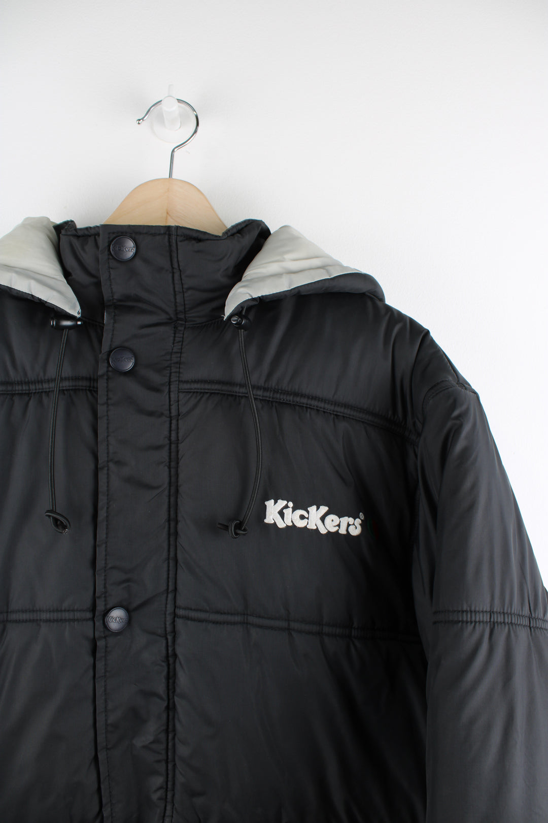 Vintage Kickers puffer jacket in black, zip up, insulated, multiple pockets, hooded and has the logo embroidered on the front.
