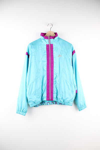 Vintage Nike Elite Shell Jacket in a blue and purple colourway, patterned design on the back, zip up, side pockets, and has the logo embroidered on the front.