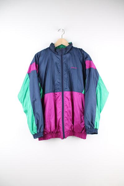 Vintage Adidas Shell Jacket in a blue, purple and green patterned colourway, zip up, side pockets, and has the logo embroidered on the front and spell out printed on the back.
