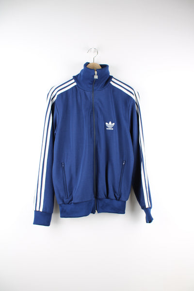 Adidas Tracksuit Jacket in a blue and white colourway, zip up, side pockets, and has the logo embroidered on the front.
