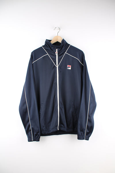 Fila Tracksuit Jacket in a navy blue and white colourway, zip up, side pockets, and has the logo embroidered on the front.