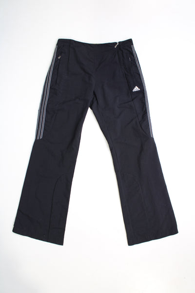 Vintage 00's black Adidas tracksuit bottoms. Feature embroidered logo on the front and three stripe detail at the sides. The track pants have an elasticated waist at the back and also have zips on the back of the legs to give them a more flared shape. good condition   Size in Label:  Womens 12