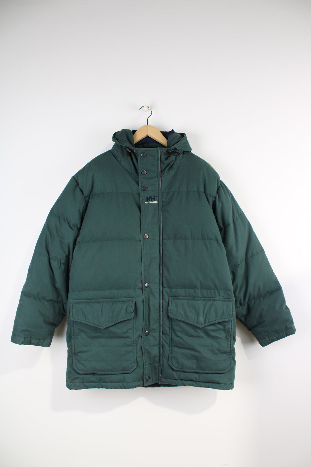 Helly Hansen Down Puffer Jacket in a dark green colourway, zip up, multiple pockets, insulated, hooded and has the logo embroidered on the chest.