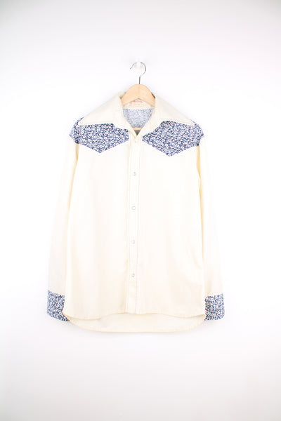 Vintage 1970's handmade western shirt in cream/off white. Features blue floral yoke/cuffs, pearl snap buttons and dagger collar 