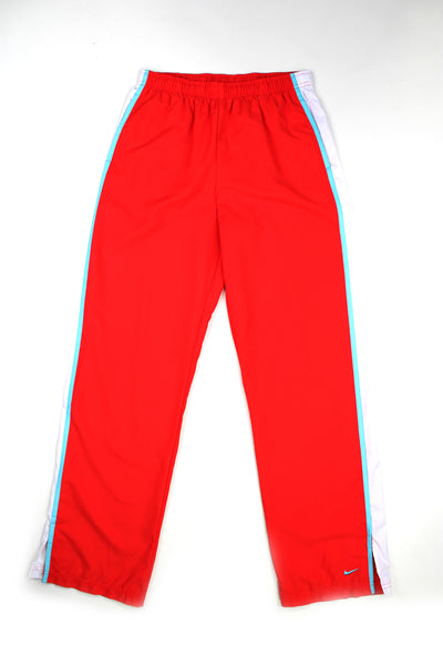 Vintage 00's Nike red tracksuit bottoms with white and blue stripe down the side, swoosh logo at the bottom of the left leg and has a elasticated waist. 