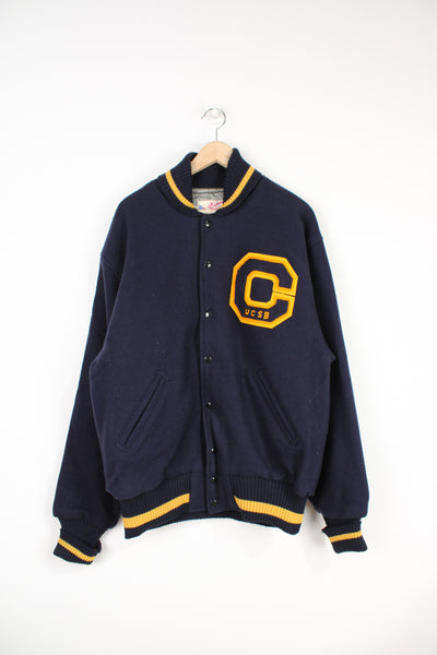Vintage UCSB navy blue, button up wool varsity jacket by Ripon Jackets features embroidered patch on the front