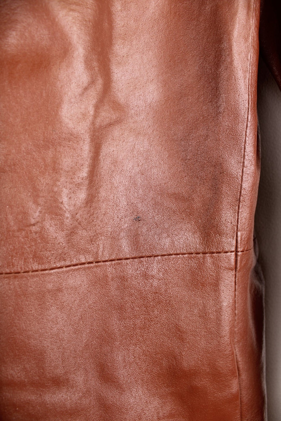 Paragon red-brown leather trench coat with two side slit pockets and concealed button closure.