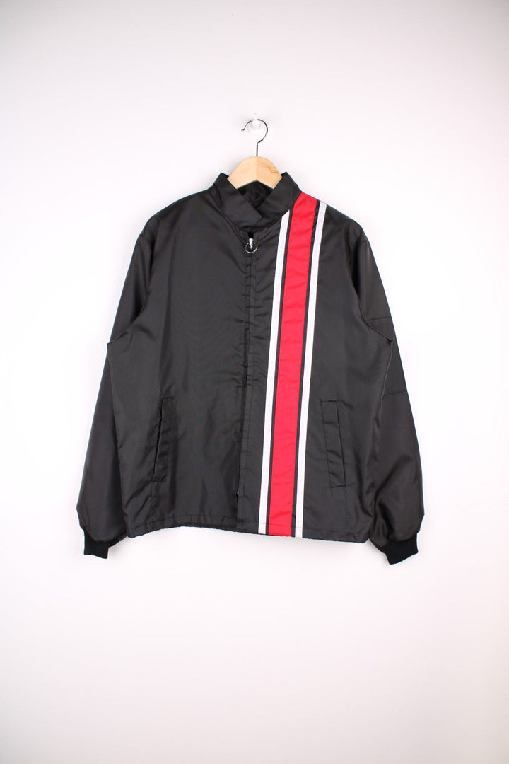 Vintage shell jacket in a black colourway. The jacket has a large printed logo on the back, and from the manufacturing of the jacket seems to date from the late 70s early 80s. Made in the USA.