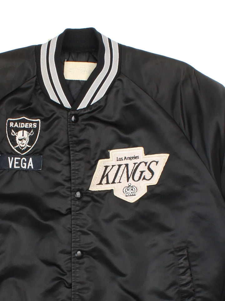 Vintage Los Angeles Kings Varsity Jacket in a black/white colourway. Buttons up with side pockets, contrast cuffs and hem. Logos embroidered on front and back.