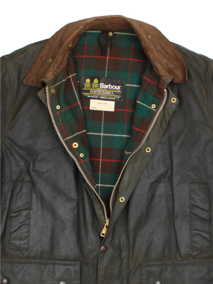 Barbour Northumbria Wax Jacket in a green colourway. Zip/button fastening, with multiple pockets, cord collar detail and checked lining.