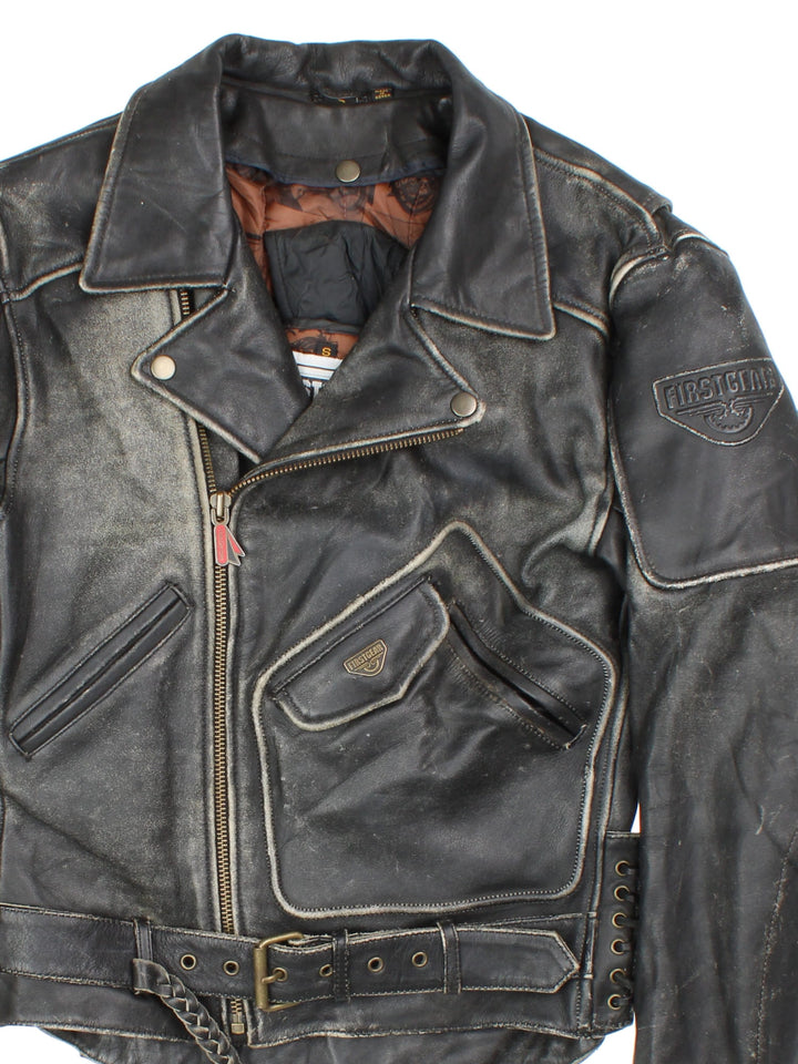 Vintage First Gear Hein Gericke Leather Biker Jacket in a black colourway. Full zip with multiple pockets, Thick padding in elbows and arms, lace up detail on the side with classic emblem on the sleeve.