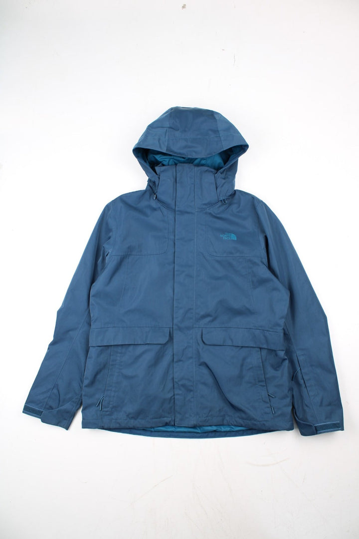 The North Face Dryvent Jacket in a blue colourway. Zips up and has multiple pockets, hooded, and has the logo printed on the front and back.