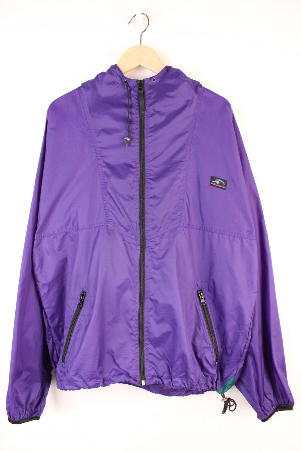 90's Helly Hansen Windbreaker in a purple colourway, zip up with side pockets, hooded and has the logo embroidered on the front.