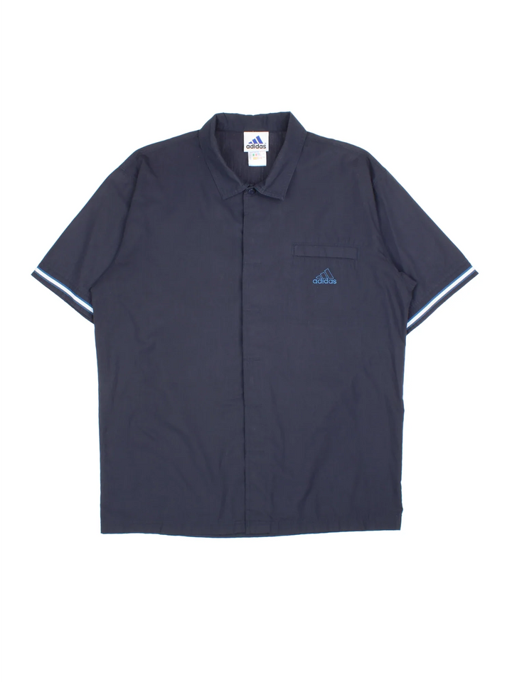 Adidas Shirt in a blue colourway. Button up fastening, with front pocket, contrast piping and embroidered logo on front/patch logo on back .