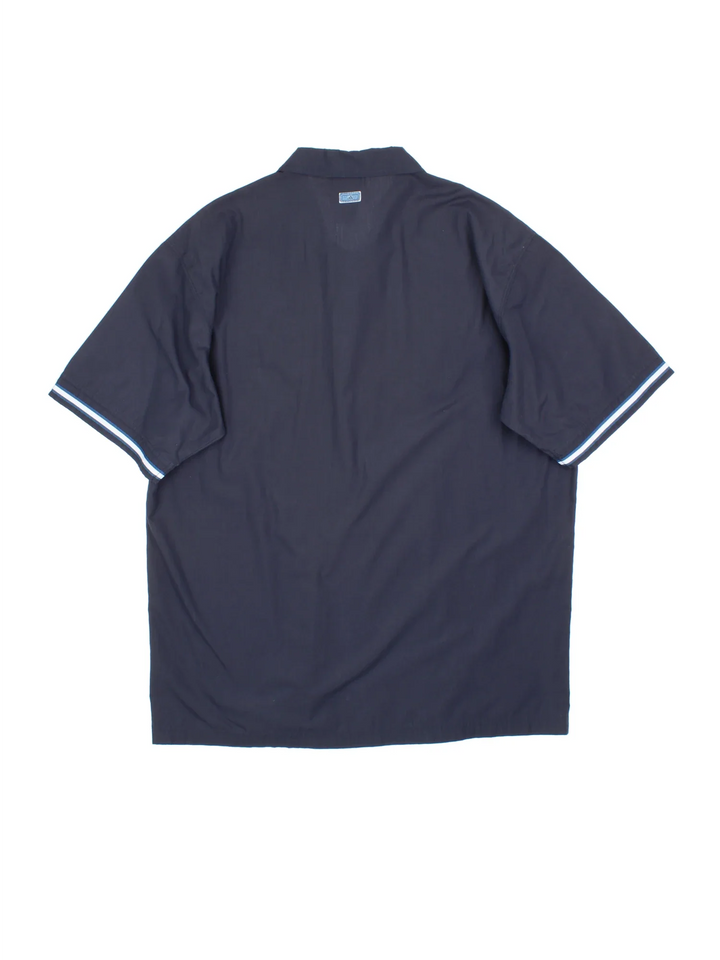 Adidas Shirt in a blue colourway. Button up fastening, with front pocket, contrast piping and embroidered logo on front/patch logo on back .