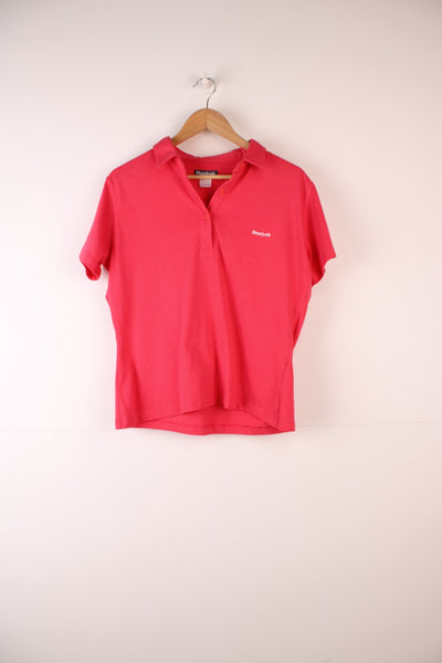 Reebok Polo Shirt in a pink colourway, button up and has the logo embroidered on the front.