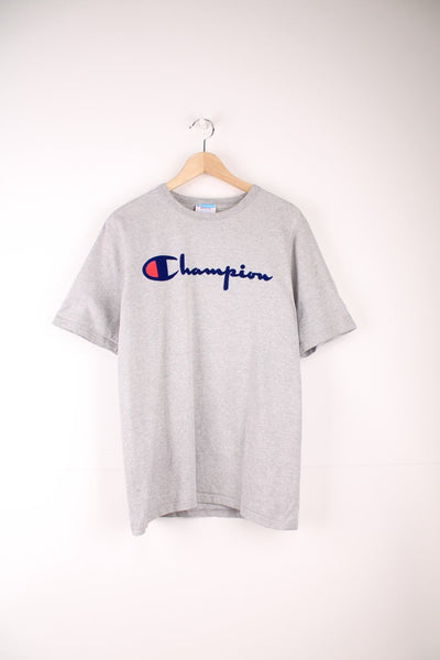 Champion T-Shirt in a grey colourway with a flocked printed spell out logo going across the front. 