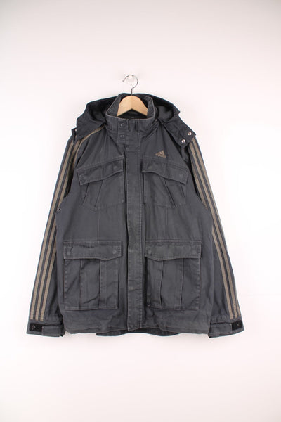 Adidas Utility Jacket in a grey colourway with the three iconic stripes going down the sleeves, zip up with multiple pockets, hidden hood, and has the logo embroidered on the front.