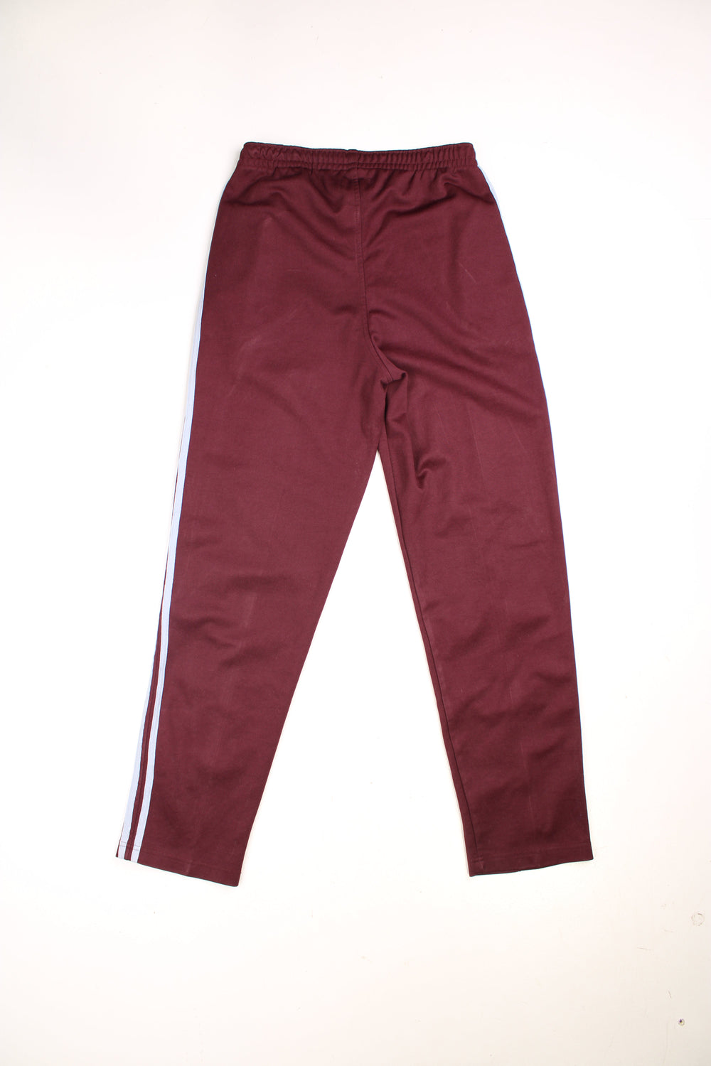 Tracksuit Bottoms in a burgundy  colourway with light blue stripes going down the sides, has an elasticated waist with drawstring, zip up side pockets, and the logo embroidered on the front.