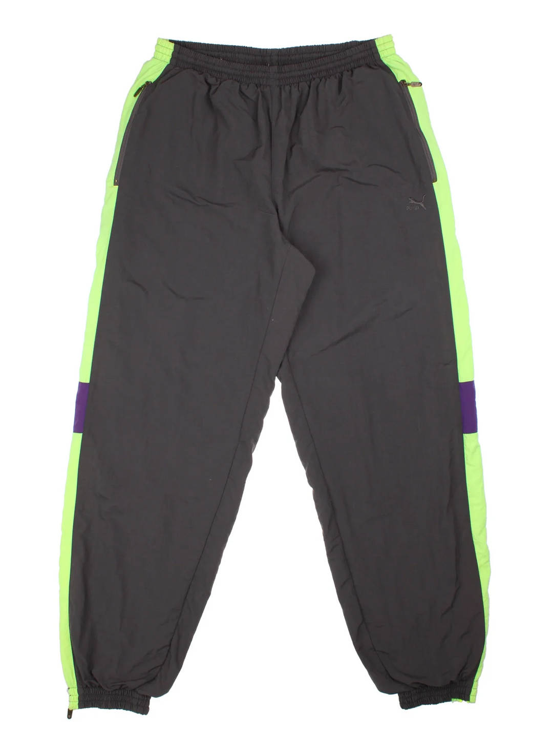 Vintage Puma Shell Pants in a grey colourway with green and purple panelling down the sides, has pockets, elasticated waist with drawstring, cotton blend lining, and the logo embroidered on the front.
