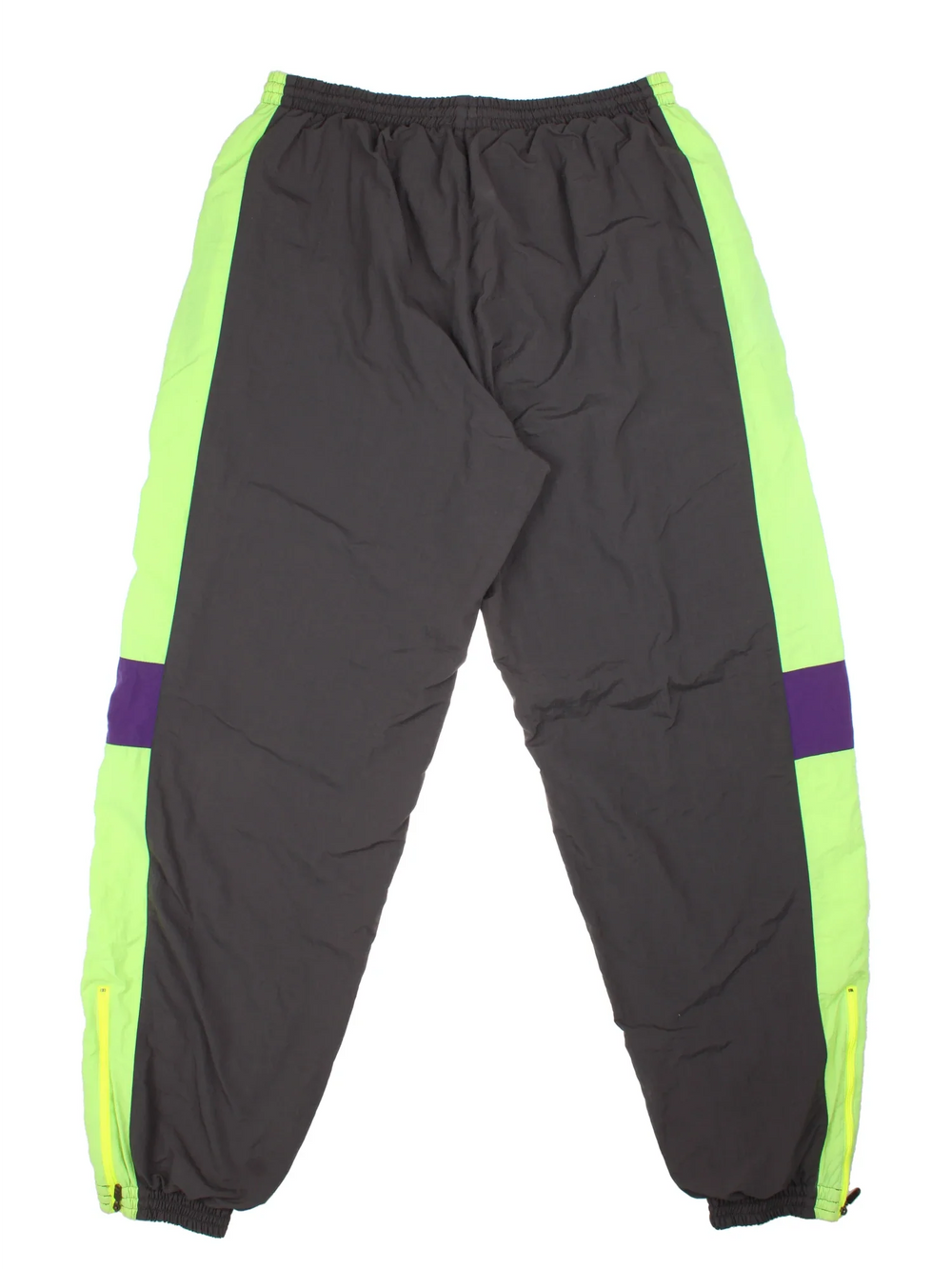 Vintage Puma Shell Pants in a grey colourway with green and purple panelling down the sides, has pockets, elasticated waist with drawstring, cotton blend lining, and the logo embroidered on the front.
