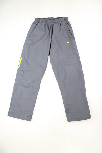 Grey and yellow Nike straight leg tracksuit bottoms with elasticated drawstring waist. Features printed logo on the front and back.