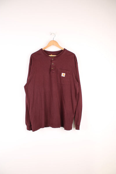 Carhartt Long Sleeved T-Shirt in a burgundy colourway, button up collar, chest pocket, and has the logo embroidered on the front. 