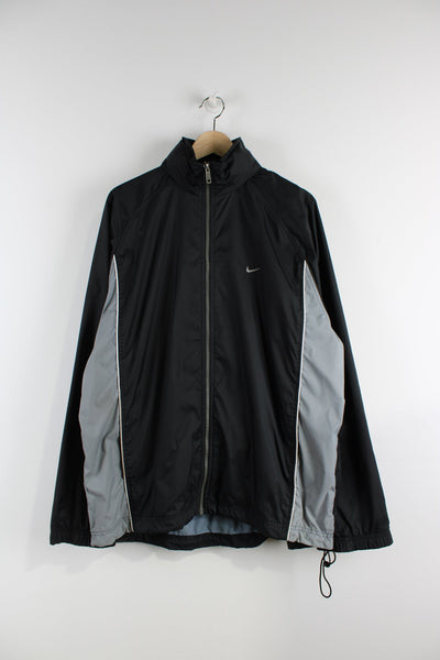 Vintage black Nike tracksuit jacket.Features embroidered logo on the chest, printed logo on the back, grey panelling on the sides and a pack away hood.