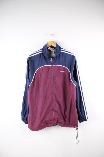 Vintage 90s Adidas tracksuit top in blue and red. Features embroidered logo on the chest and signature three stripes on each sleeve.