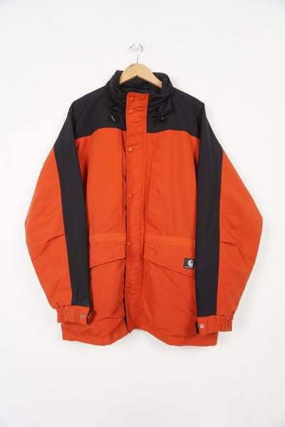 Red and black Carhartt outdoor coat with multiple pockets and foldaway hood
